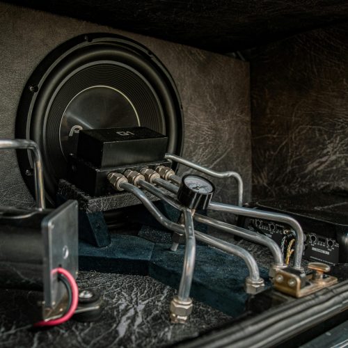 Close-up of an intricate car audio and hydraulic setup with metal components.